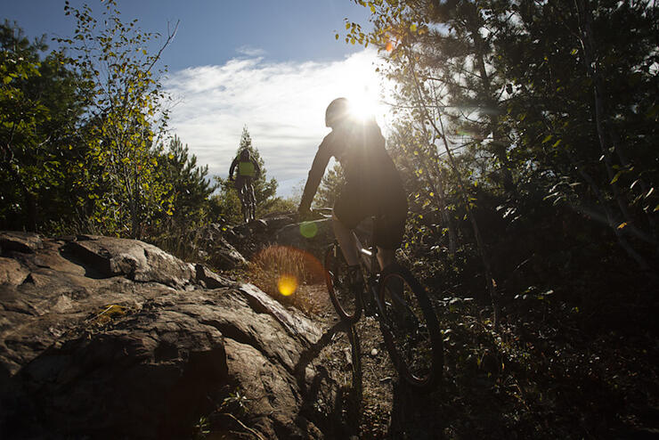 Cyclists rides along a rocky offroad bike trail on a sunny day