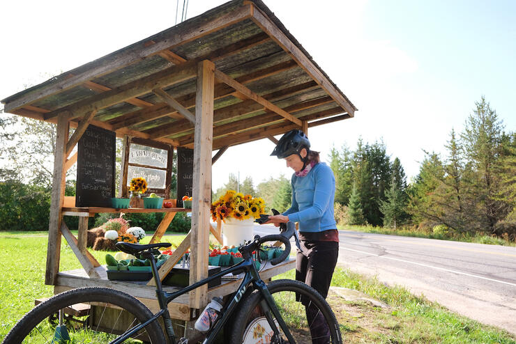 Woman cyclist stops and purchases food from a roadside stand