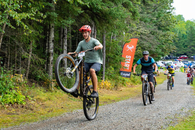 teenage boy pops a wheelie while taking part in a bike race