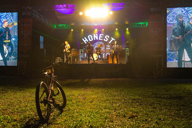 a bicycle is parked in front of a lighted stage while musicians perform in the evening after a race