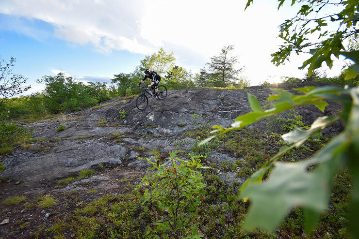 man rides over a rocky hill in summer at Walden