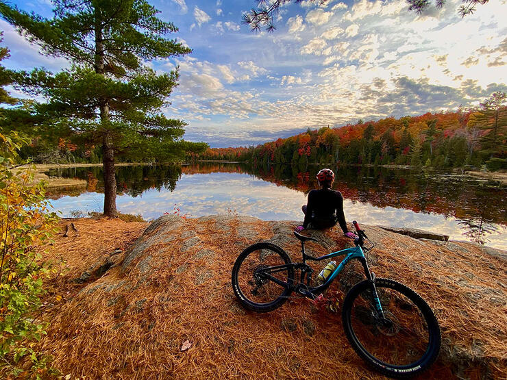 woman sightsees over a fall lake on a break from a cycling tour
