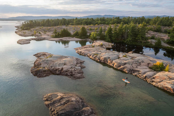 Overhead shot of paddleboarder next to rocky shore.