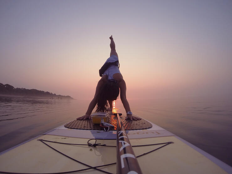 woman performs yoga poses on a standup paddleboard