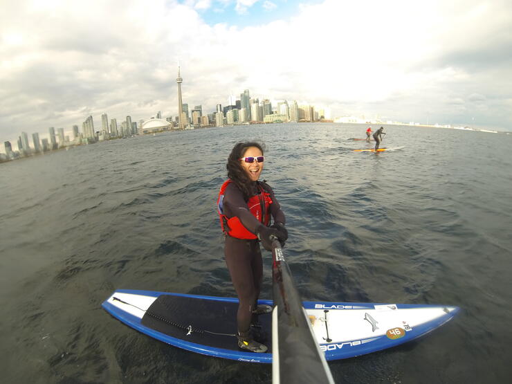 woman takes photo with selfie stick while standing on a SUP