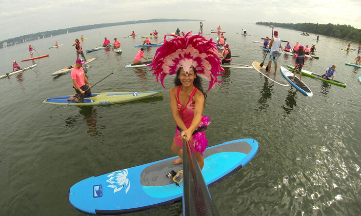 woman poses with Carnival-style headdress at a SUP fundraising event