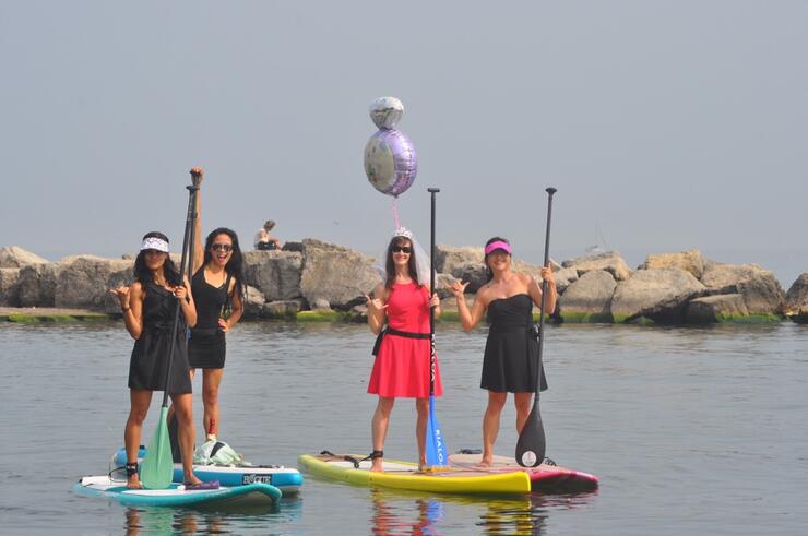 a group of women on standup paddleboards at a floating party
