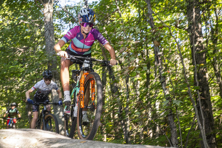 Emily riding her bike down a rock with kids following behind.