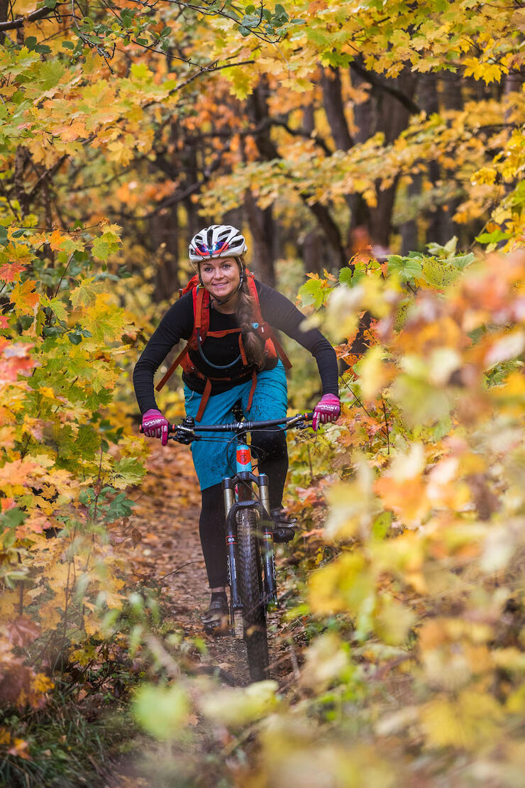 Young woman mountain biking through colourful forest