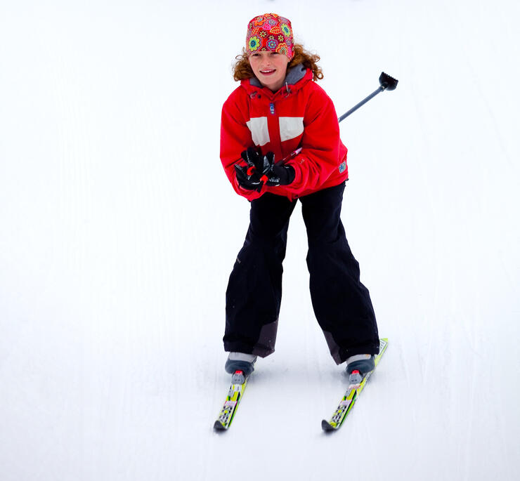 Young girl in tuck position while cross-country skiing. 