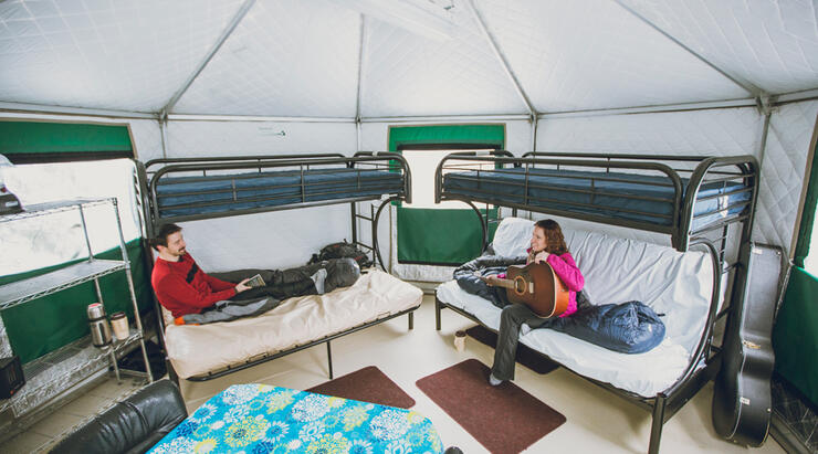 A couple sitting on bunk beds inside a yurt. 