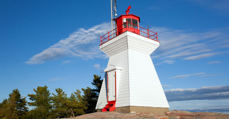 white lighthouse with red top perched on rock on Georgian Bay