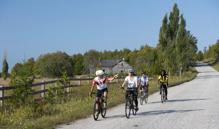 Four cyclists riding on a country ride by farmland. 