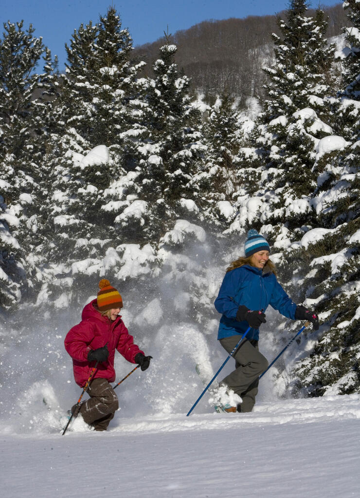 Woman and girl running on snowshoes in deep powder snow