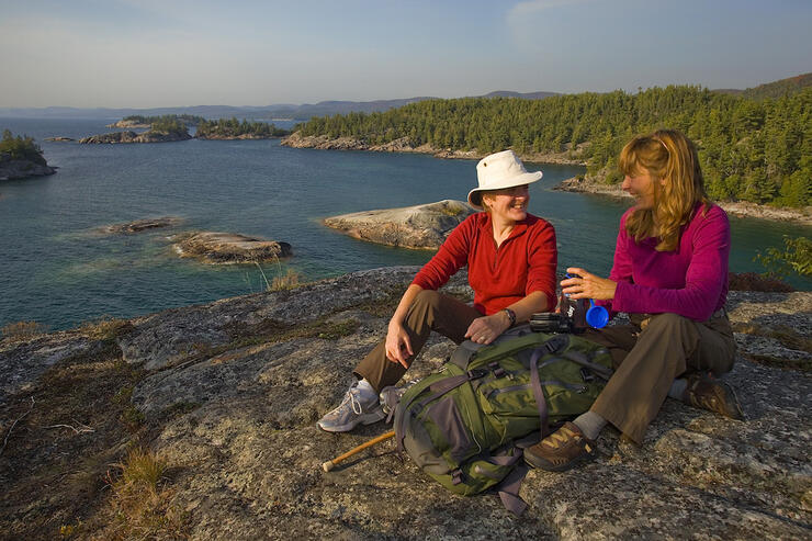 Two women sitting on rock overlooking Lake Superior coast