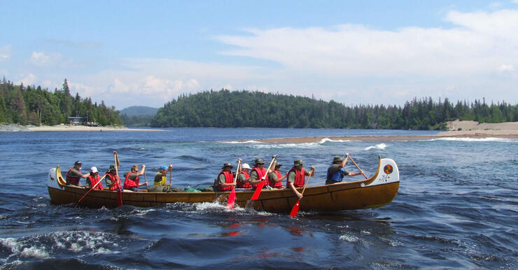 Eleven people paddling a replica voyageur canoe on Lake Superior 