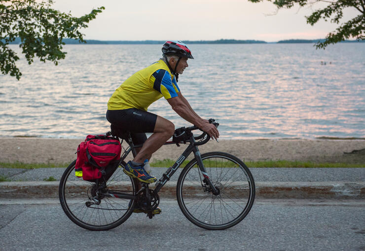 Man riding a bike on a bike path by a lake. 