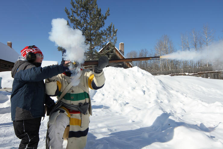 Two people shooting an old gun in the winter