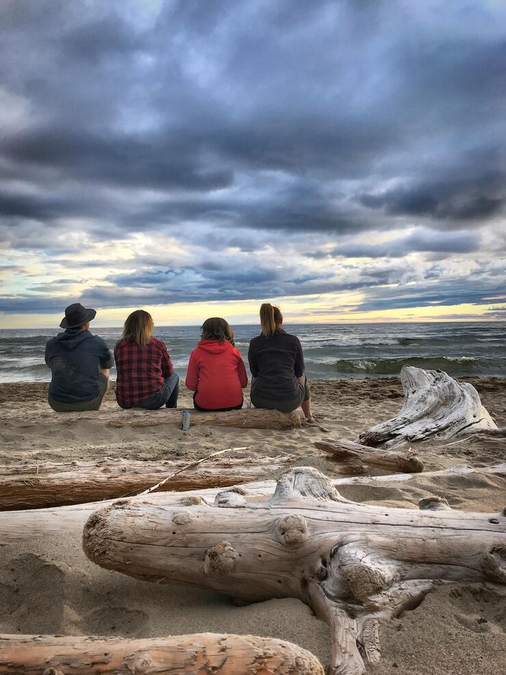 our people sitting on sand facing the water.