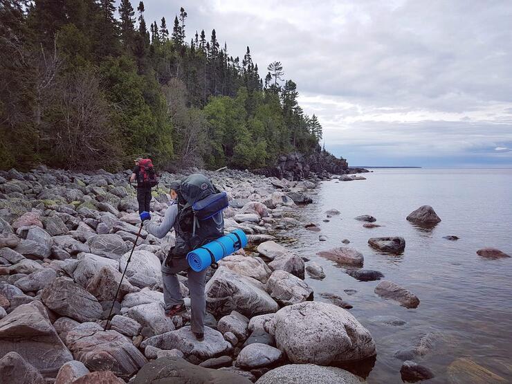 Two people backpacking on rocks at water's edge