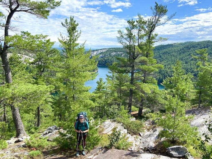 Backpacker standing on hill that leads down to a lake