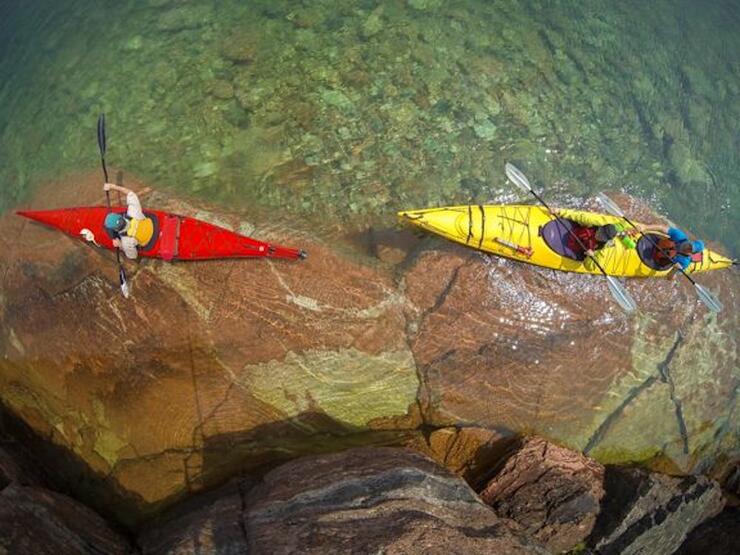 Overhead shot of two kayakers paddling in clear water.
