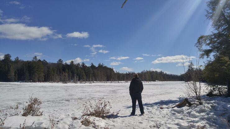 Man standing at edge of frozen lake.
