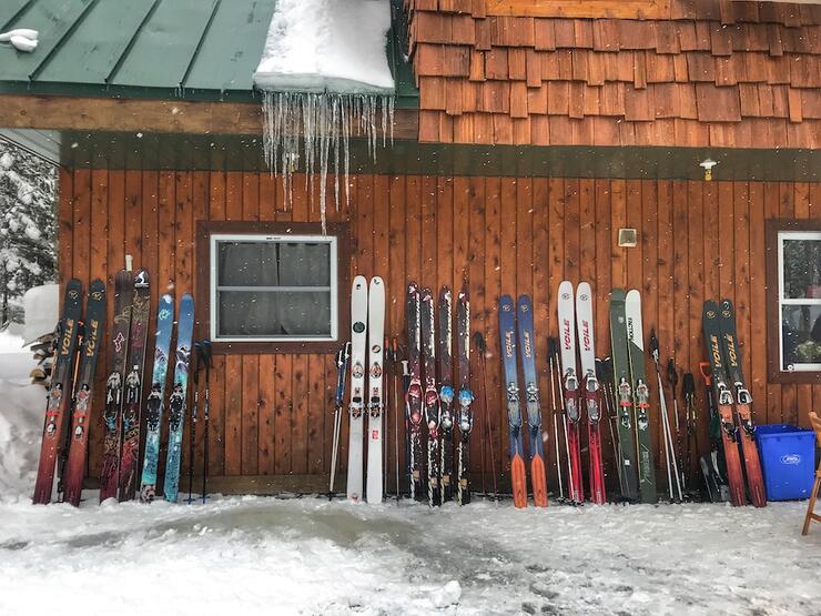 Skis leaning up against wooden building in the snow.