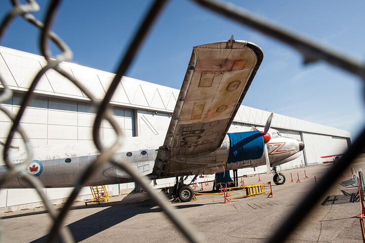 Side of an airplane through a chainlink fence 