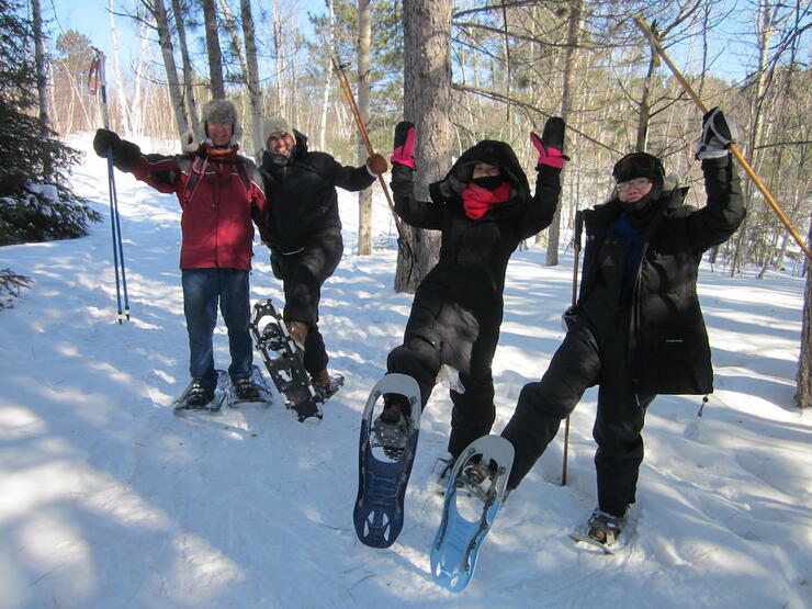 Four people wearing snowshoes on a trail