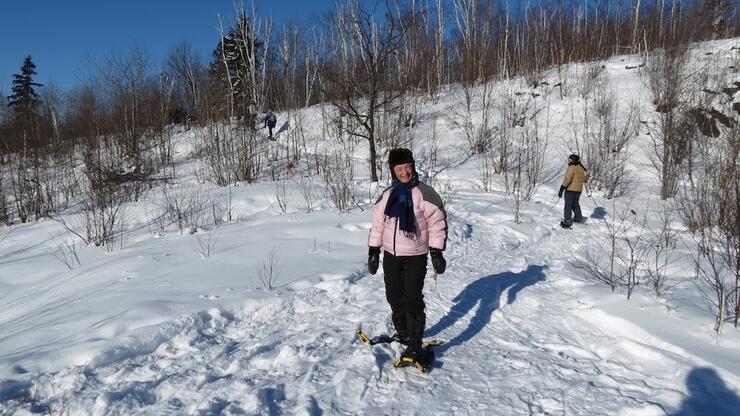 Woman on snowshoes with man in background.
