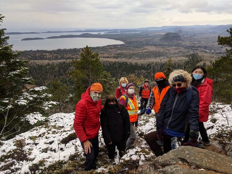 Group of people wearing masks at top of lookout over lake in the winter