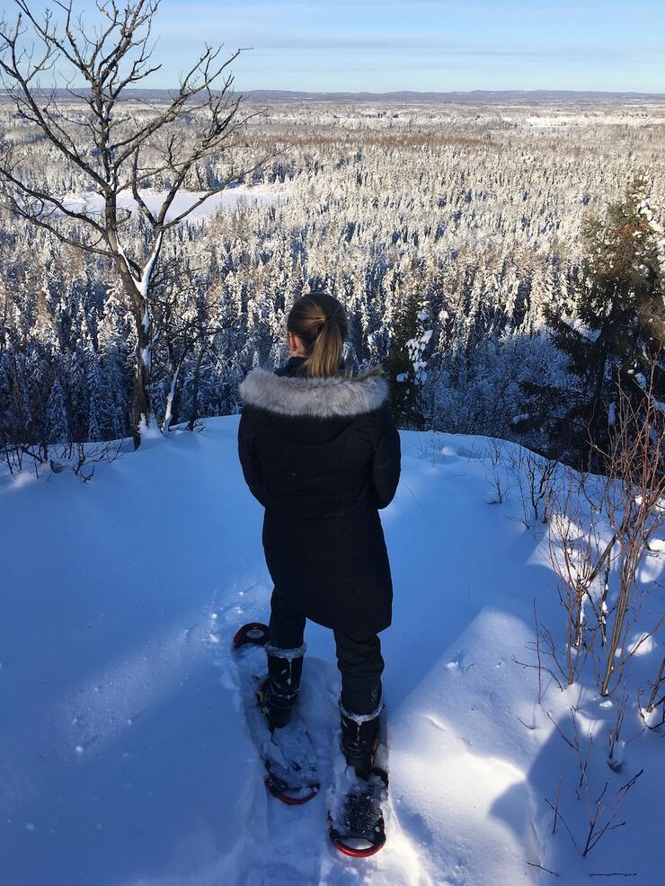 Woman on snowshoes at top of snowy lookout