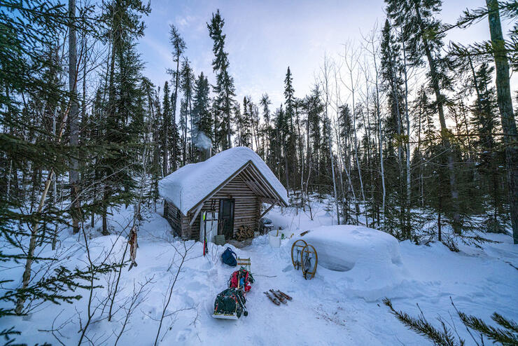 A cabin in the woods covered in snow