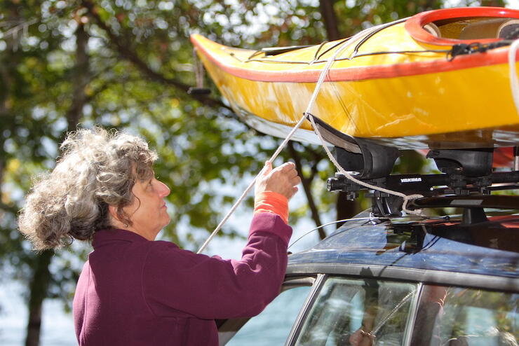 Woman untying canoe from roof rack