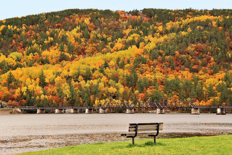 a Mattawa bench along the river in fall with Laurentian Mountains behind