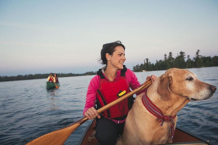 Woman paddling in a canoe with a dog