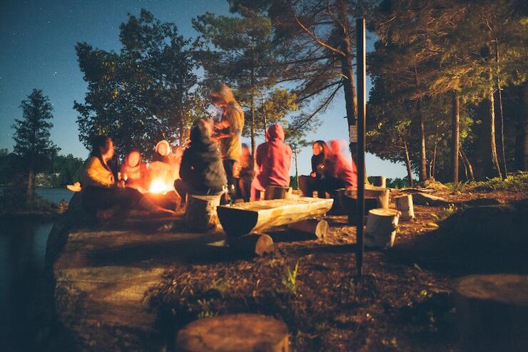 People sitting next to fire at night