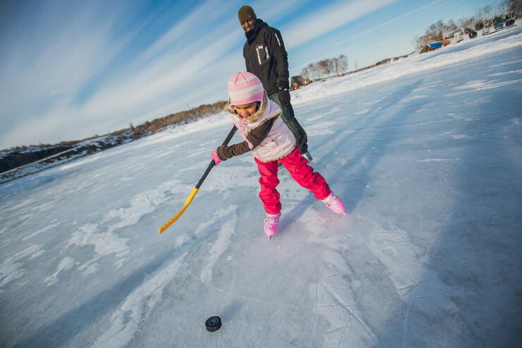 Father and daughter playing hockey on a frozen lake