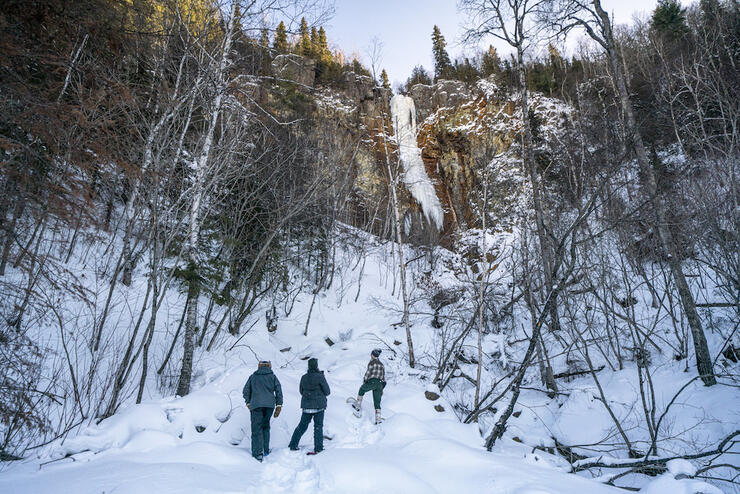 Snowshoers approaching a frozen waterfall.
