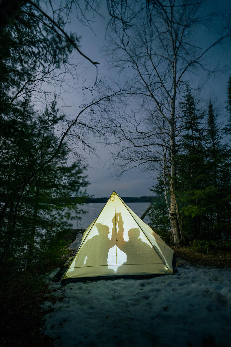 Two people in a hot tent on the edge of a winter lake