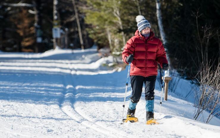 A woman snowshoes on groomed trails in the forest