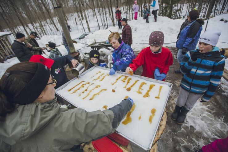 A crowd gathers to eat some maple snow candy