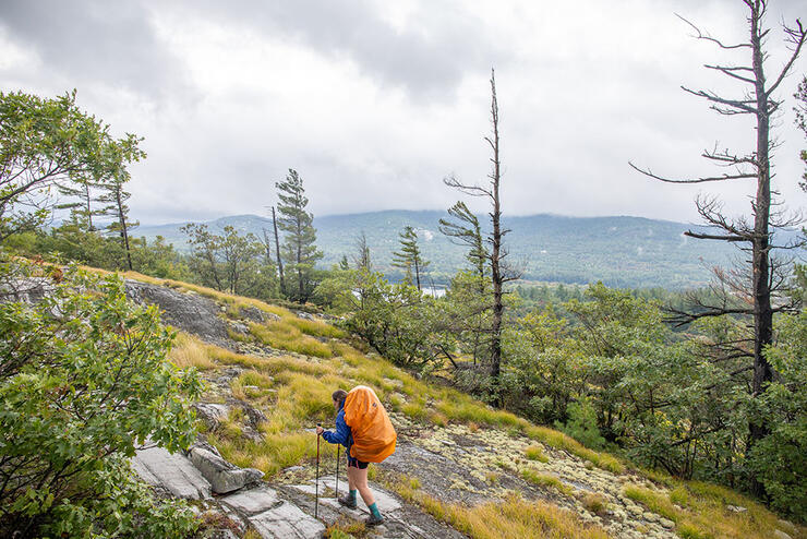 woman hikes with backpack and poles on La Cloche Mountains