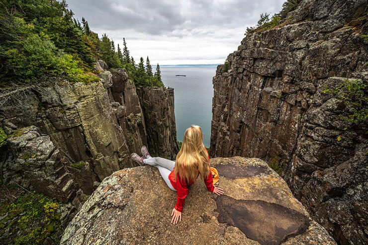 woman sits and admires the view from a stone outcropping at Sleeping Giant