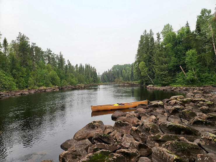 an empty yellow canoe sits at the river's edge in Point Grondine