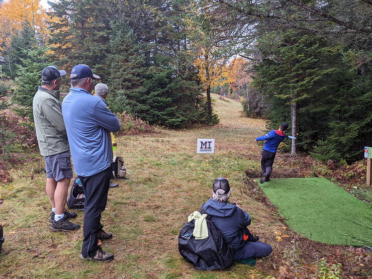 people watch as a person throws a frisbee while playing disc golf