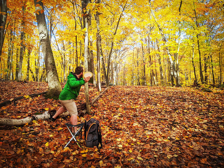 man prepares to throw frisbee in forest at Bondi Cottage Resort Wolf Tracks Disc Golf Course