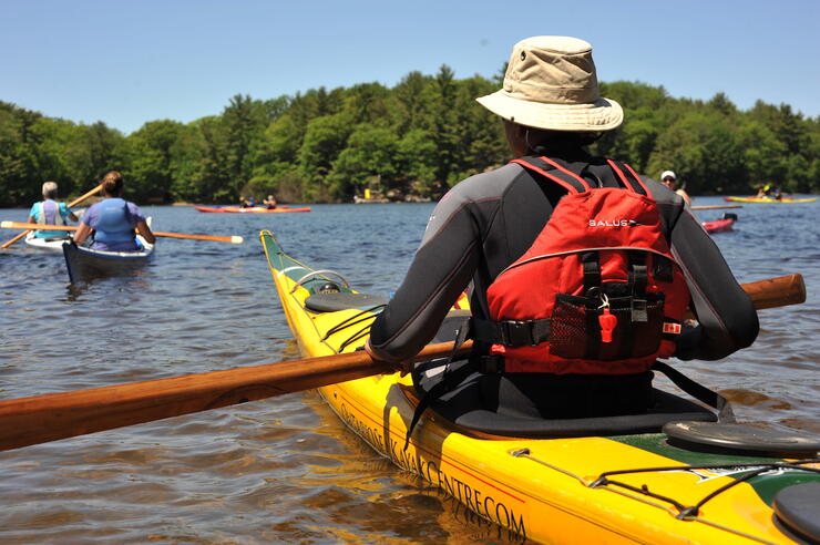 Back view of kayaker with other kayaks in water 