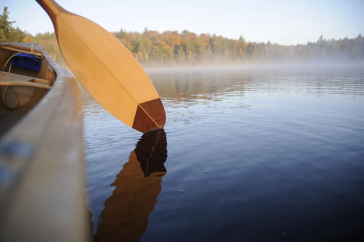 Paddle over the side of a canoe on a foggy lake